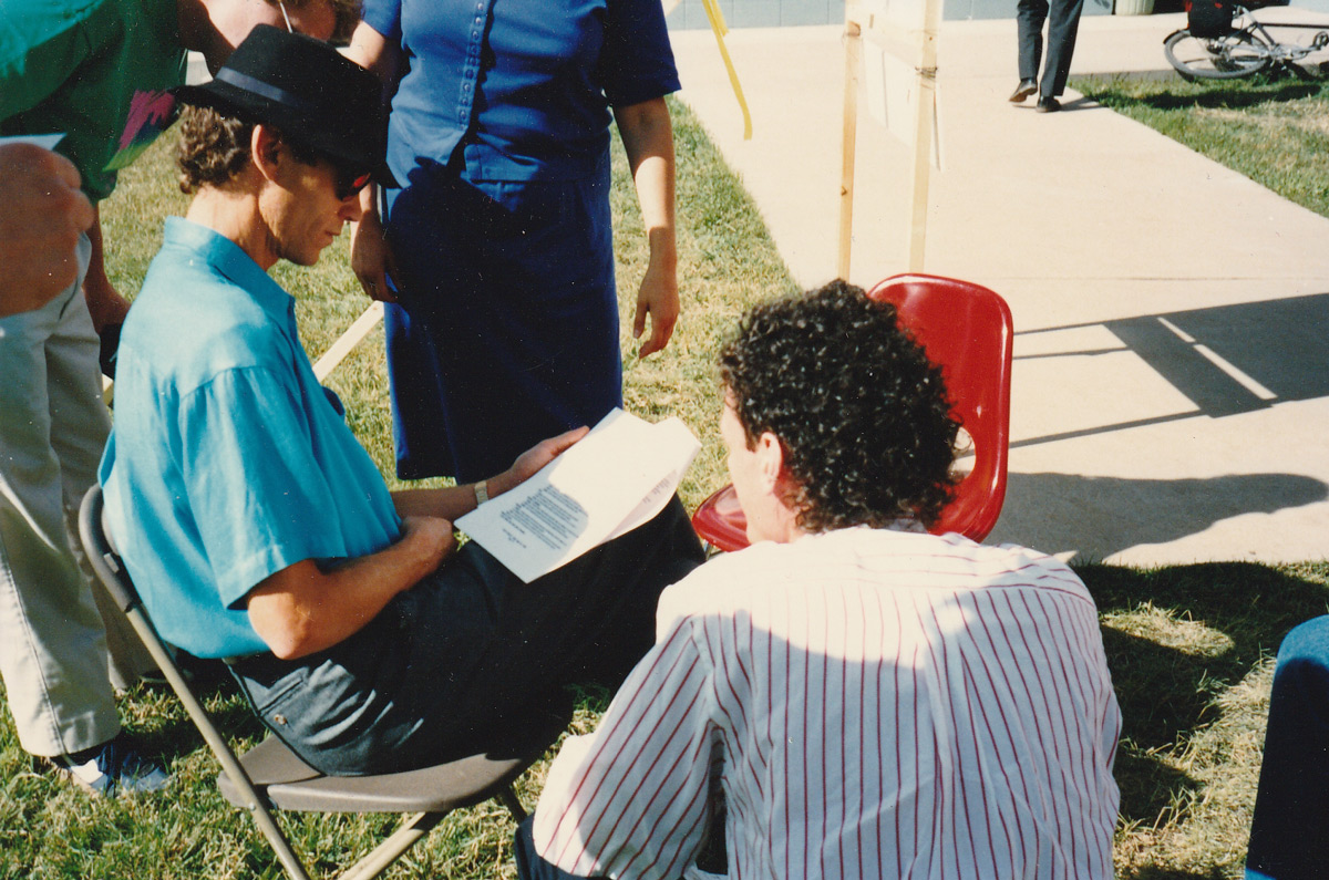 John Robbins Sitting with Fans hat and sunglasses