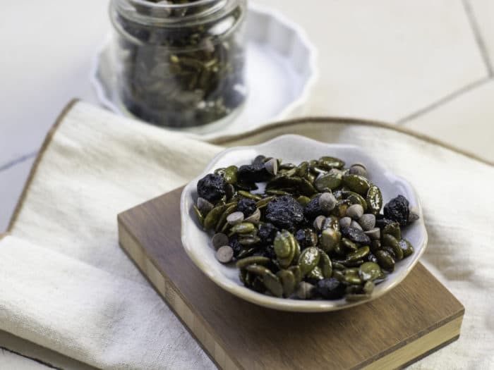 coffee beans on a bowl with a jar of coffee beans on the side