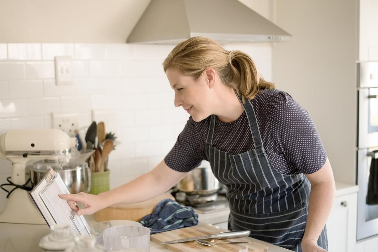Mature woman reading cookbook in the kitchen.