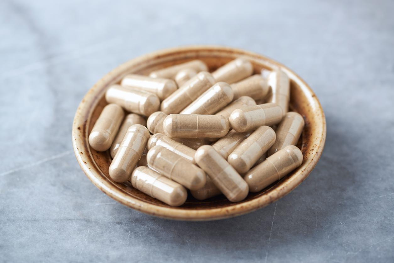Ashwagandha (Withania somnifera) capsules. Concept for a healthy dietary supplementation. Bright stone background. Copy space.