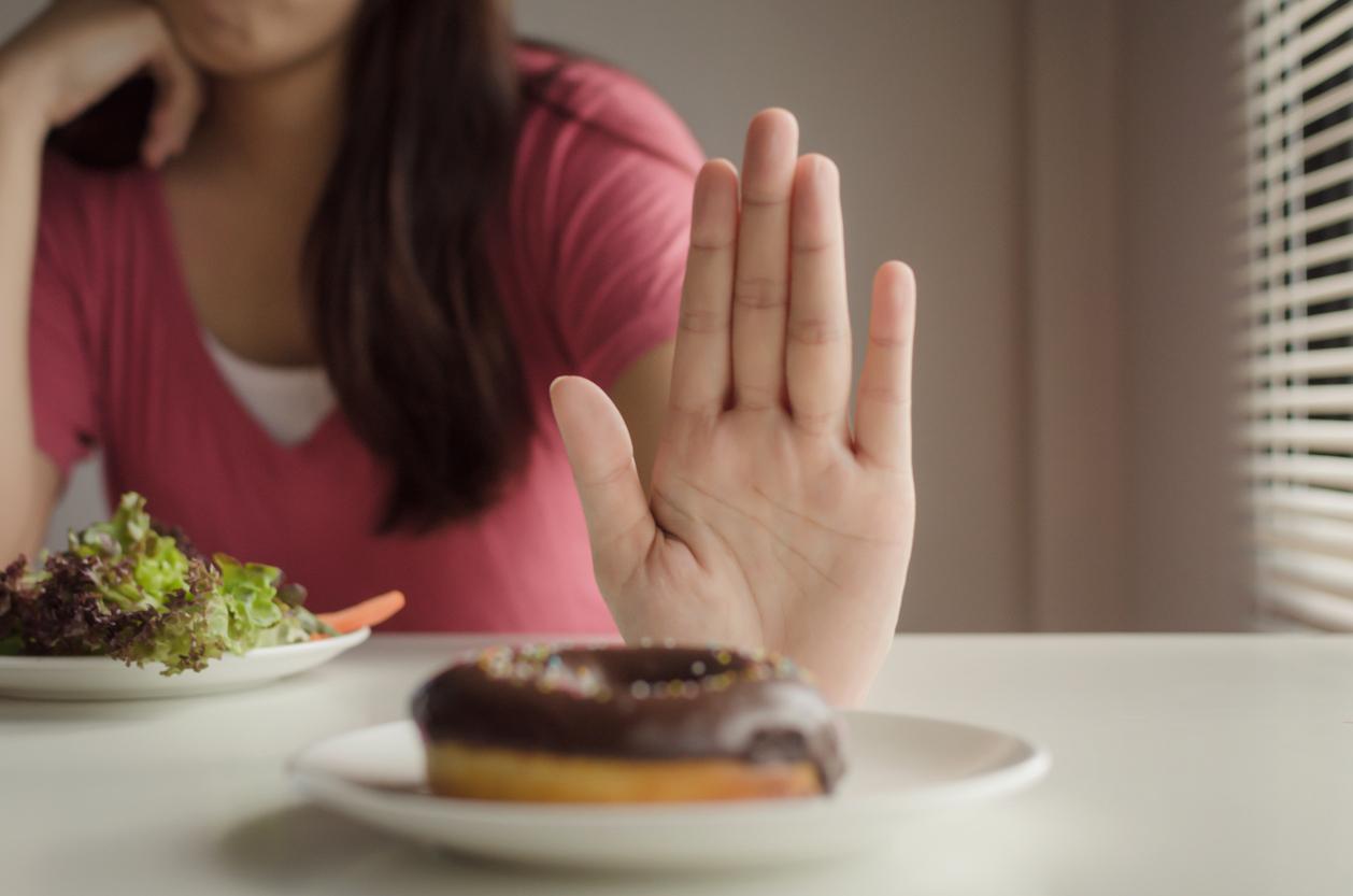 Diet. young woman refuse delicious chocolate glazed donut, junk food, unhealthy food and eating fresh vegetables salad for good health at home, weight loss, lifestyle, healthy food and dieting concept