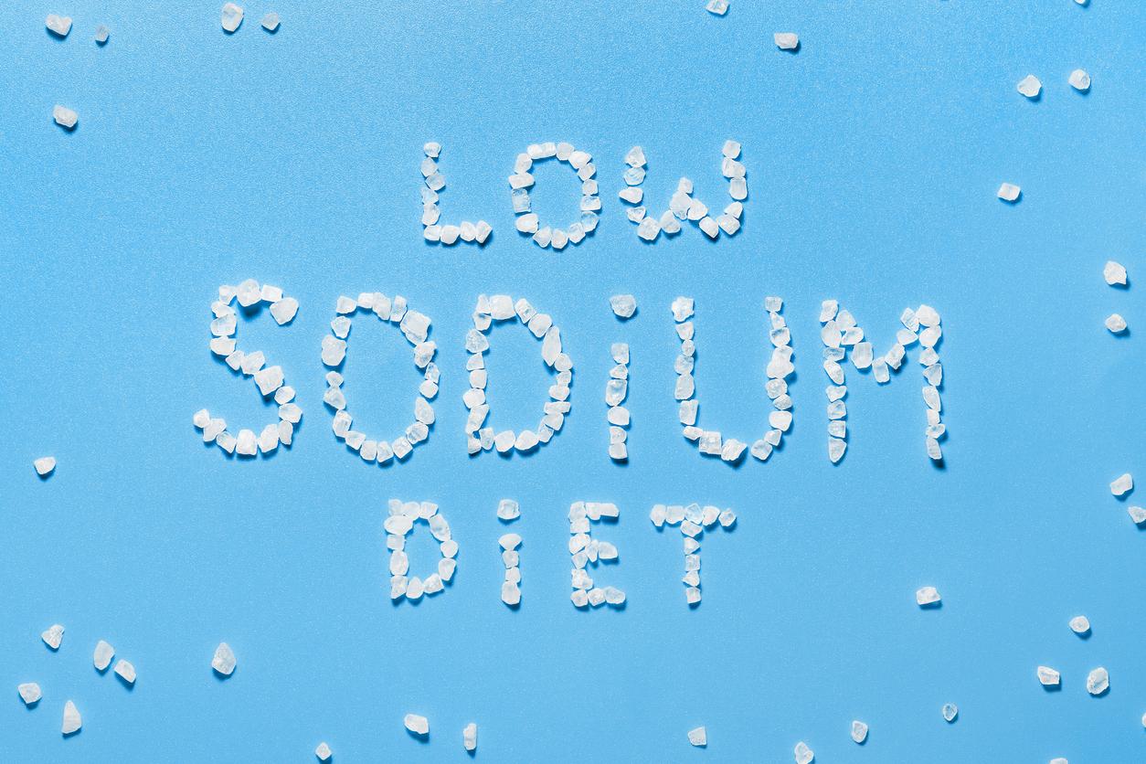 The concept of a low sodium diet. Prevention of hypertension and heart disease. Salt crystals on blue background.