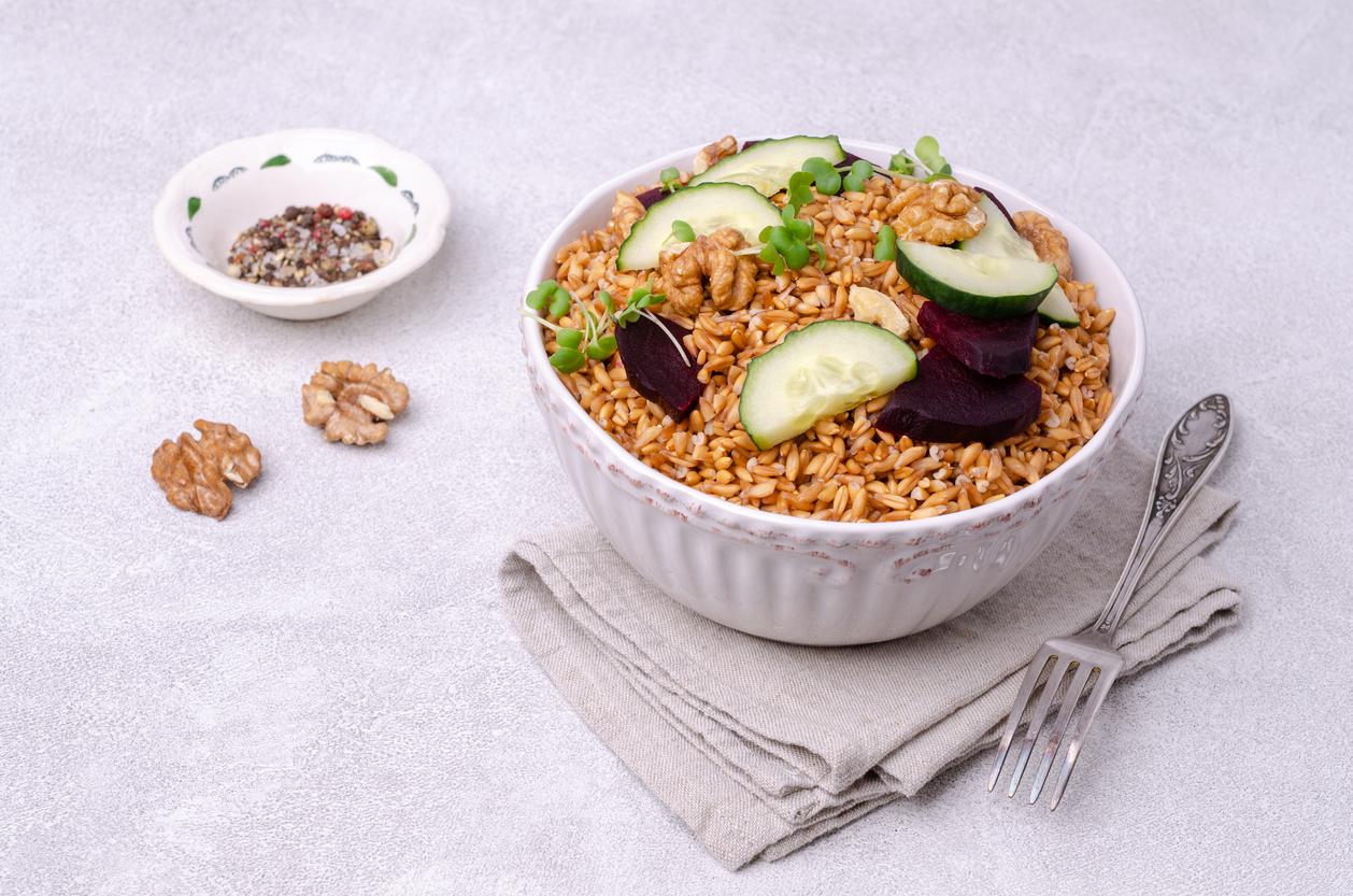 Wheat with vegetables in a ceramic bowl on a cement background. Selective focus.