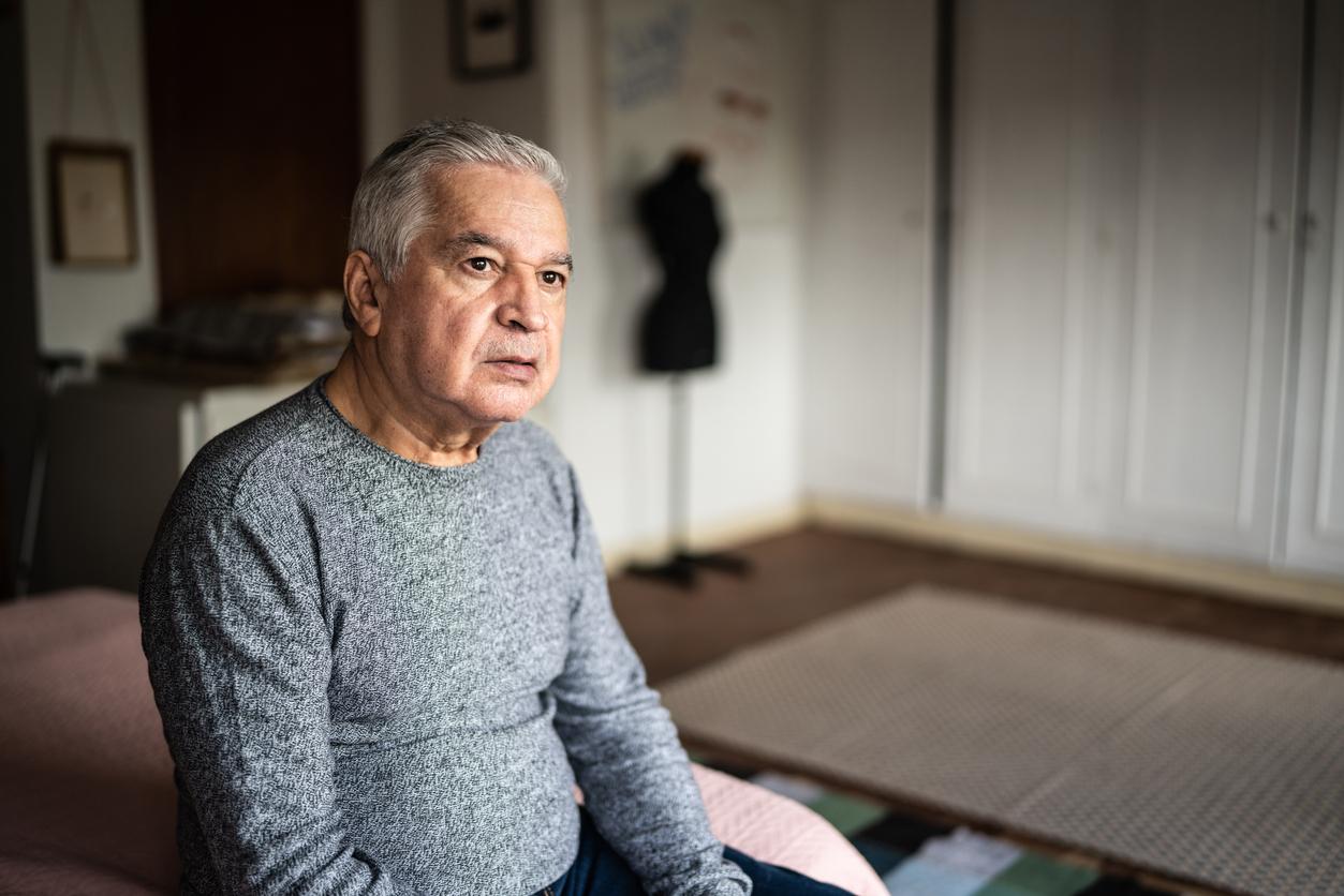 Senior man sitting on the bed and looking away
