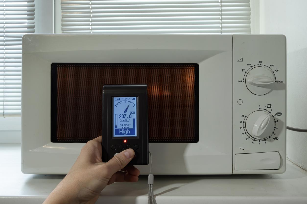 Device measures electromagnetic radiation from a microwave oven. A man's hand holds a device for research