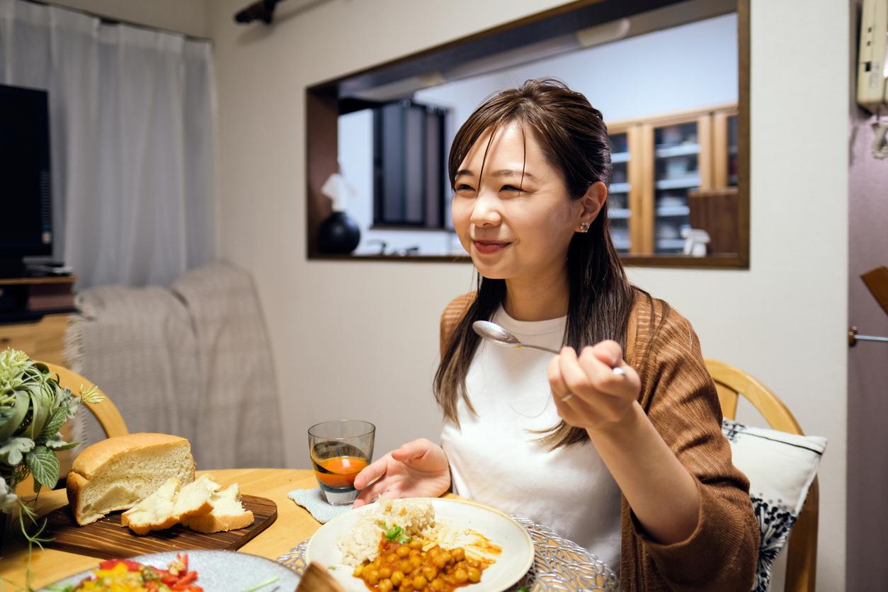 Asian woman eating chickpea dish at home
