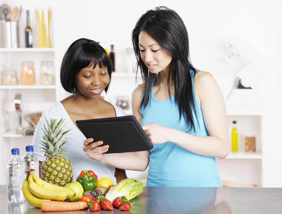 A portrait of a dietician showing client a diet/ food plan on a digital tablet.