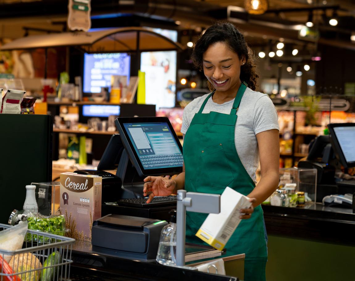Happy cashier working at the supermarket ringing up groceries