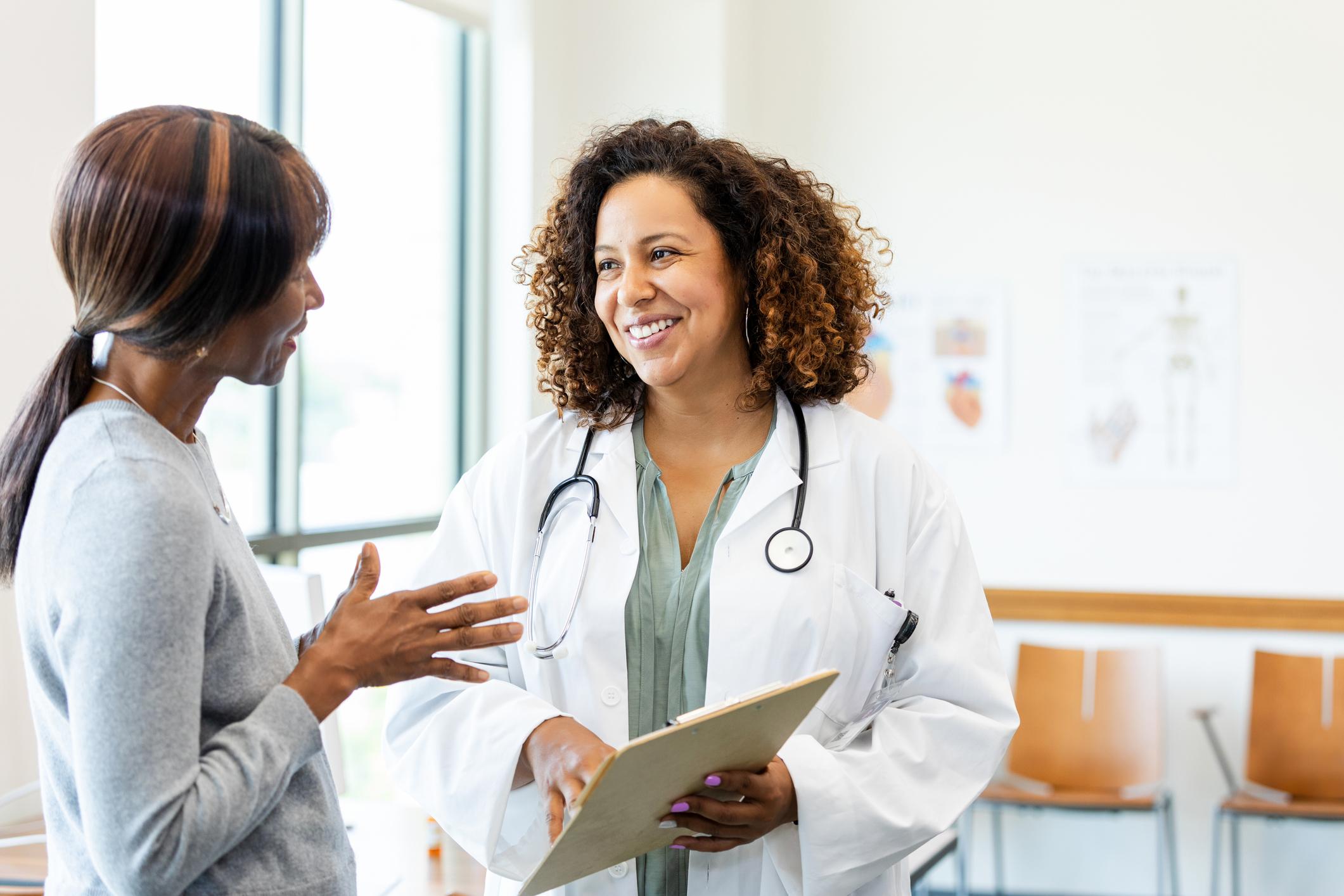 Female doctor and patient talking; healthcare and medicine; indoors; smiling; communication.