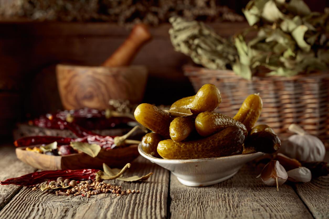 Pickled cucumbers with ingredients on an old wooden table. 