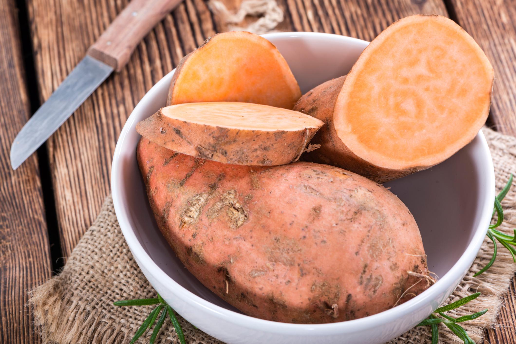 Raw Sweet Potato (detailed close-up shot) on wooden background