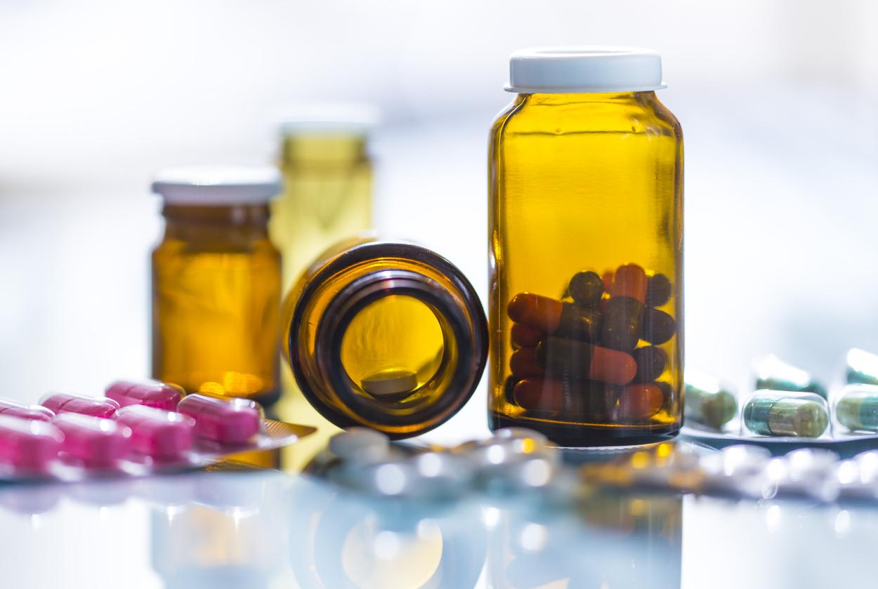 medicines in blister packaging and brown glasses in backlight