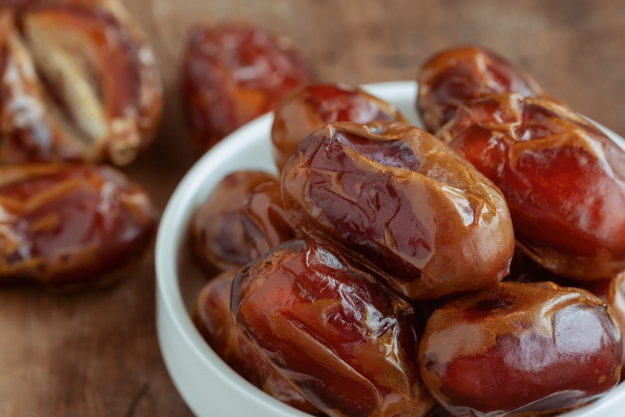 Khalas date palm on wood table in close up with copy space for background or wallpaper. Dates fruit is food for Ramadan or medjool. Delicious dried fruit with sweet taste and have high fiber.